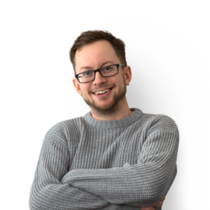 Man with folded arms wearing a grey jumper, short brown hair, beard and glasses.